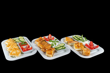 Special kinds of Burek with cheese, spinach,minced meat and patatoes.Fresh and tasty, served on a white plate with tomatoes and cucumber with a glass of tea.