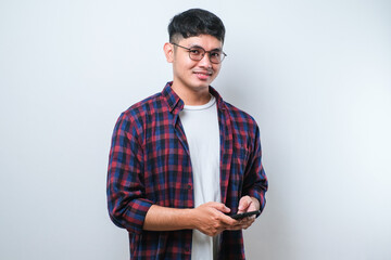 Smiling young good looking Asian man using smartphone to get in touch with family and friends