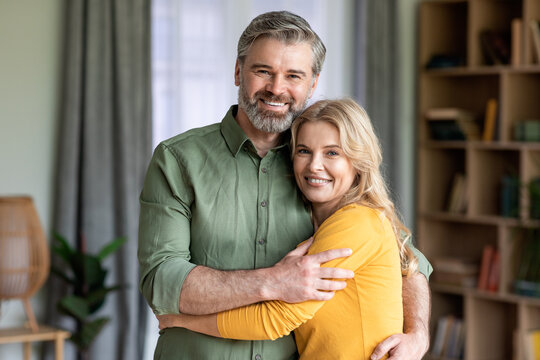 Portrait Of Middle Aged Romantic Couple Embracing And Smiling At Camera