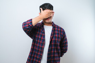 Young handsome asian man covering one eye with hand, confident smile on face and surprise emotion.