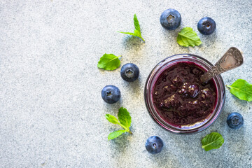 Blueberry jam in the glass jar with fresh berries. Top view with copy space