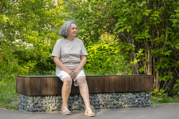 Sad lonely old woman reflects on outdoor life. Wrinkles on the face, gray hair. Retirement age.