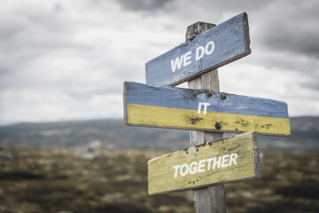 we do it together text quote on wooden signpost outdoors in nature. War in ukraine concept.