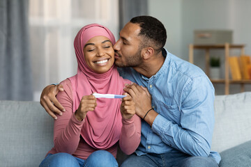Portrait Of Happy Black Muslim Couple Holding Positive Pregnancy Test