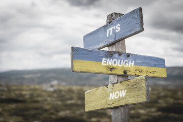 it's enough now text quote on wooden signpost outdoors in nature. War in ukraine concept.
