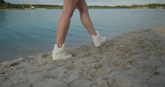 Close up of female feet walking on golden sand at the beach