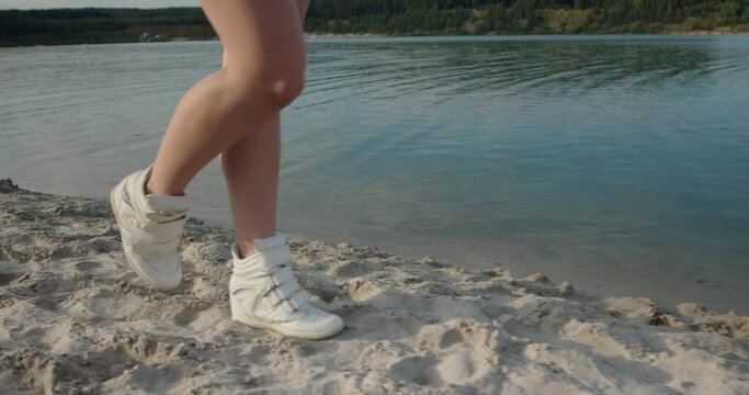 Close up of female feet walking on golden sand at the beach