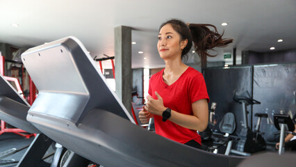 Fototapeta premium Asian young woman is having jogging on the treadmill