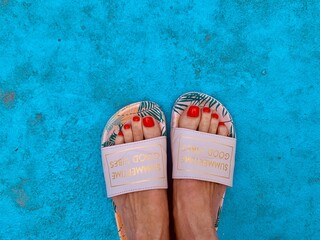 Female feet with flip flop on blue background 
