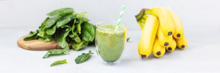 Vegetarian green smoothie with avocado, spinach leaves, banana in glass on gray concrete...