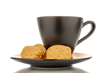Several zoological cookies with a black cup on a saucer, macro, isolated on a white background.