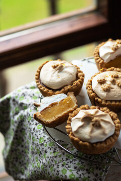 Lemon curd tartlets with whipped meringue on a wire rack.