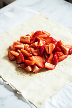 Summer strawberry galette with almond flakes in making. Food preparation concept.