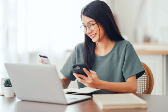 Online payment, Happy asian woman holding a credit card and using smart phone and laptop for online shopping