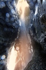 Grota w wąwozie w Lichtensteinklamm w austriackich Alpach, z kapiącą z góry wodą i pędzącym w dole potokiem Großarler Ache - obrazy, fototapety, plakaty