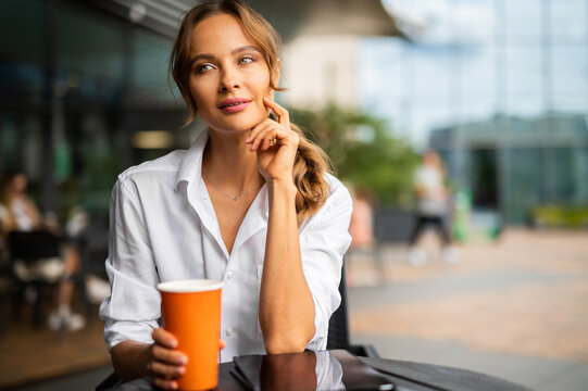 Young businesswoman on a coffee break, smiling in a pensive expression
