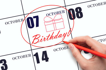 The hand circles the date on the calendar 7 October, draws a gift box and writes the text Birthday....
