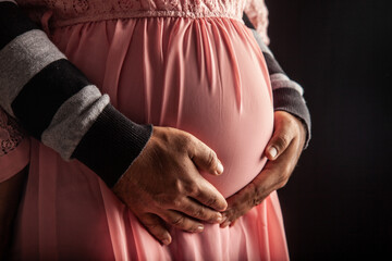 Male hands hold the belly of pregnant woman.