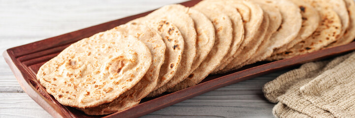 Homemade Indian Traditional Flatbread called Chapati on a white wooden background. Baked indian flatbread. Indian - obrazy, fototapety, plakaty