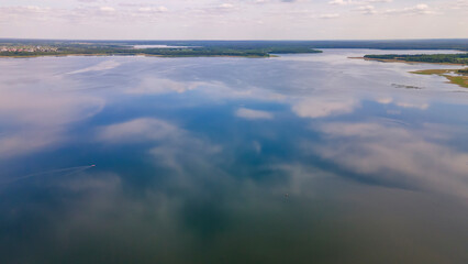 Aerial view of lake with sky reflection. Blue lake and green forest. Image for design. Space for text.