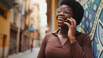 Portrait of Afro female talking over mobile phone. Cheerful Afri