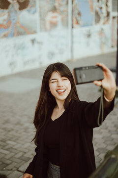Mujer joven tomándose fotografías (selfie) con una cámara analógica. Concepto de gente, estilos de vida y viajes.