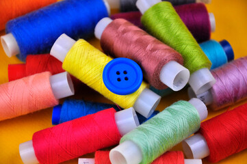 Set of multicolored buttons and Spools threads on a yellow background. Blurring.