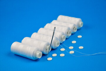 White thread spools and buttons for sewing clothes. Blurring.