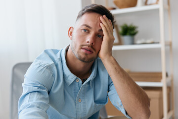 Naklejka premium Sad frustrated young man reclines on hand looks aside think about difficult life decision bad news health problem. Upset guy have depression need professional psychology help. Copy space for ad