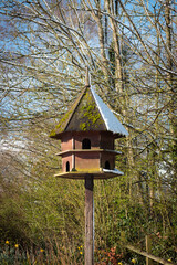 Naklejka premium Hexagonal wooden bird house and feeder with Spring snow in bright sunshine