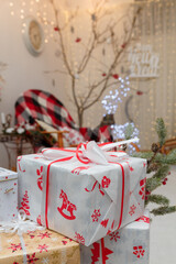Wrapped present boxes on blurry Christmas background with garlands boke. White paper with red ribbon and bow, Christmas pattern