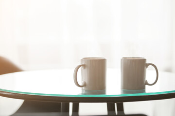 two cups of coffee on a glass table.