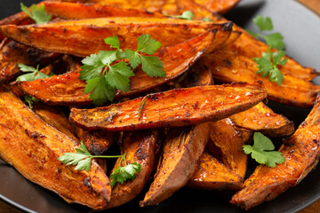 Baked Sweet potato wedges, fries served on black plate