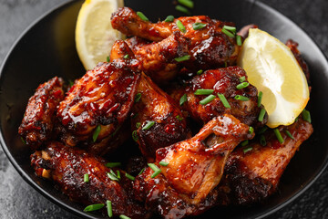 Baked chicken wings with sweet chili, honey sauce in black bowl