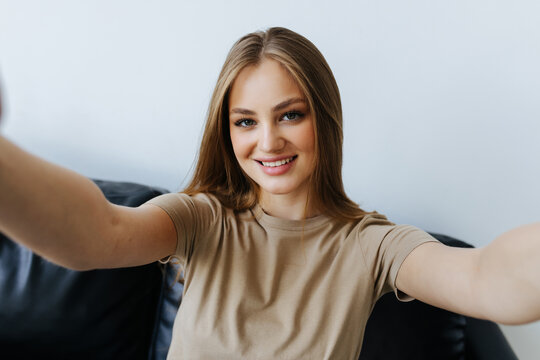 Portrait of beautiful woman taking a self-portrait with her smartphone at home.