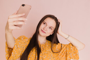 Beautiful woman taking selfie on pink background