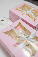 Two pink present boxes decorated with ribbon and bow. Packaging of cupcakes and meringue roll. Homemade sweets. Soft focused shot