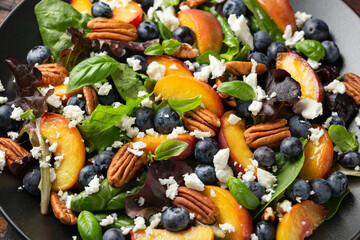 Peach, blueberry salad with vegetables, feta cheese and pecan nuts. Healthy summer food