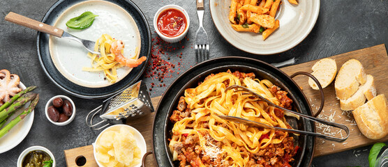 Assortment of Italian pasta with traditional sauces for dinner on dark background. Homemade food concept