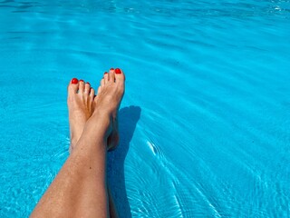 feet with red pedicure in pool. Copy space 