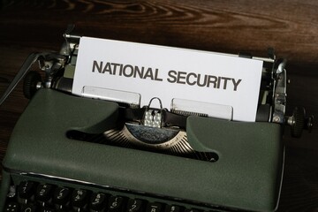 National security is written in large letters on a white piece of paper on an old army green typewriter.