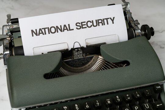 National security is written in large letters on a white piece of paper on an old army green typewriter.