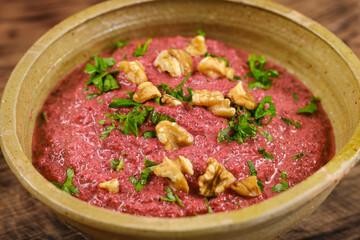 healthy homemade beetroot dip sauce hummus, in rustic clay bowl served with walnuts and parsley