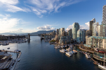 Obraz premium Aerial View of Granville Island in False Creek with modern city skyline and mountains in background. Downtown Vancouver, British Columbia, Canada.
