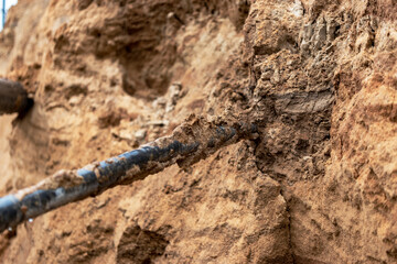 The high voltage electrical cable is laid in a trench under existing engineering sewerage networks. Laying a high voltage cable for supplying buildings with electricity.