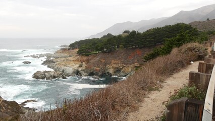 Rocky craggy ocean shore, foggy misty weather. Sea water waves crashing on beach. California scenic...