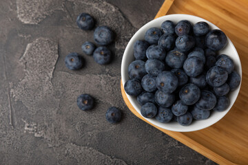 Blueberries in a ceramic bowl on a black textured background. Ripe and fresh blueberries. Vitamins. Healthy food. Juicy berry.Copy space.Place for text