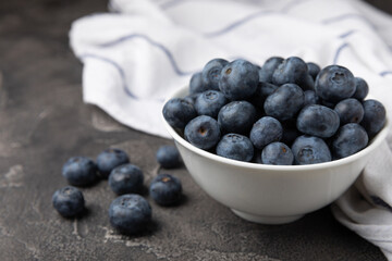 Blueberries in a ceramic bowl on a black textured background. Ripe and fresh blueberries. Vitamins. Healthy food. Juicy berry.Copy space.Place for text