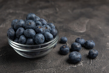 Blueberries in a ceramic bowl on a black textured background. Ripe and fresh blueberries. Vitamins. Healthy food. Juicy berry.Copy space.Place for text