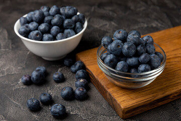 Blueberries in a ceramic bowl on a black textured background. Ripe and fresh blueberries. Vitamins. Healthy food. Juicy berry.Copy space.Place for text